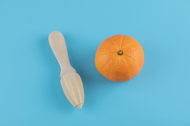 Orange und hölzerne Reibahle auf blauem Tisch.