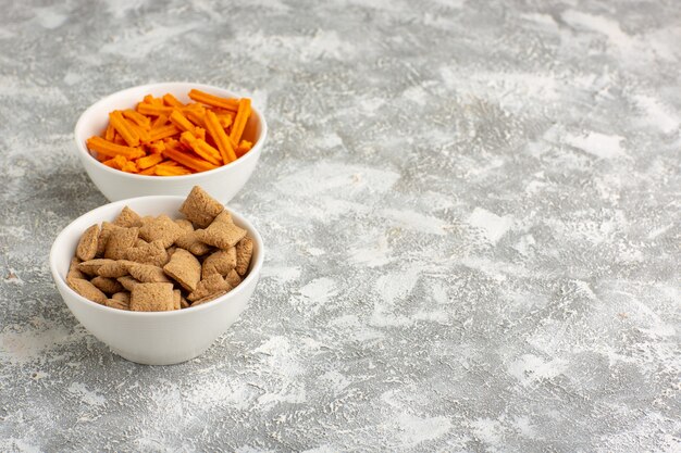 Orange Zwieback der Vorderansicht mit Kissenplätzchen auf dem weißen Schreibtisch