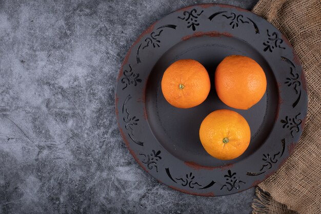 Orangen in einer dunklen Platte. Draufsicht.