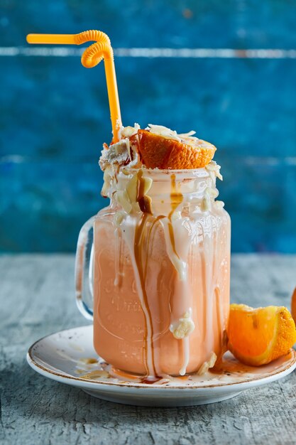 Kostenloses Foto orangen-smoothie mit sahne, stroh und orangenscheiben in der marmoroberfläche