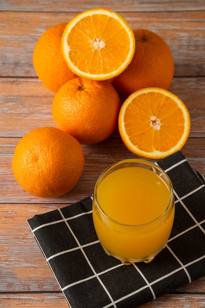 Orangen und ein Glas Saft auf einem schwarzen Küchentuch, Draufsicht