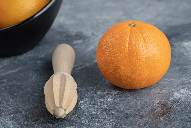 Orangen und Quetschwerkzeug auf Marmortisch.