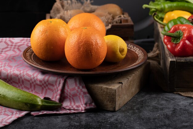 Orangen und Zitrone auf einer Platte auf einem Stück Stein.