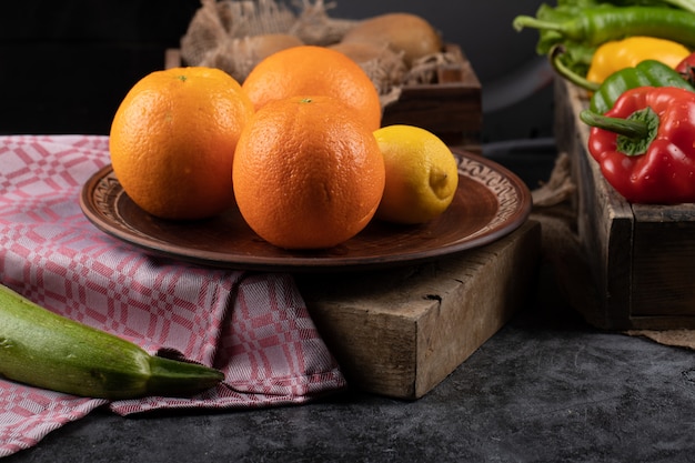 Orangen und Zitrone auf einer Platte auf einem Stück Stein.