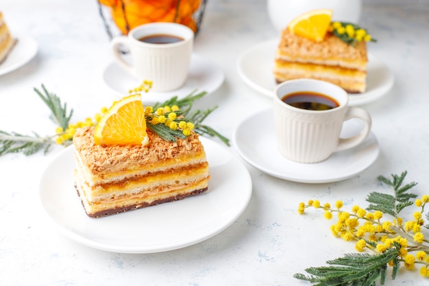 Orangenkuchen dekoriert mit frischen Orangenscheiben und Mimosenblüten auf Licht