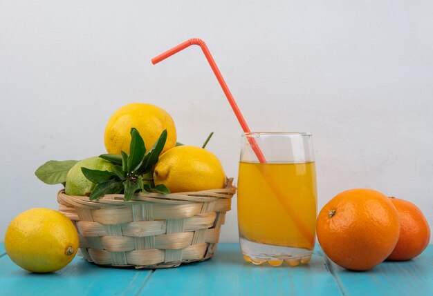 Orangensaft der Vorderansicht in einem Glas mit einem Strohorangen und Zitronen in einem Korb