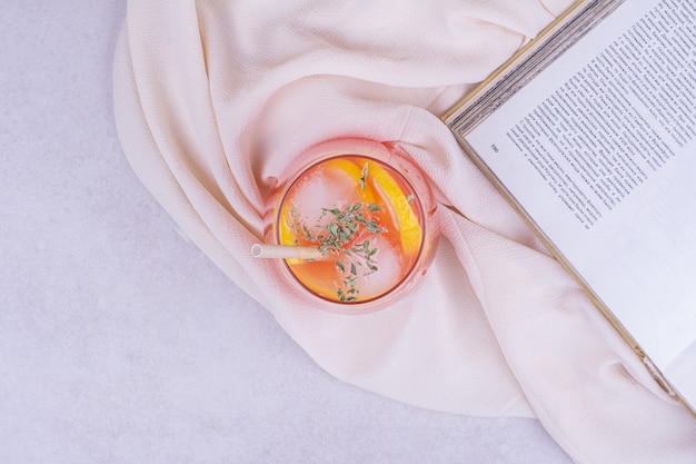 Orangensaft mit Fruchtscheiben und Gewürzen auf weißem Tisch.