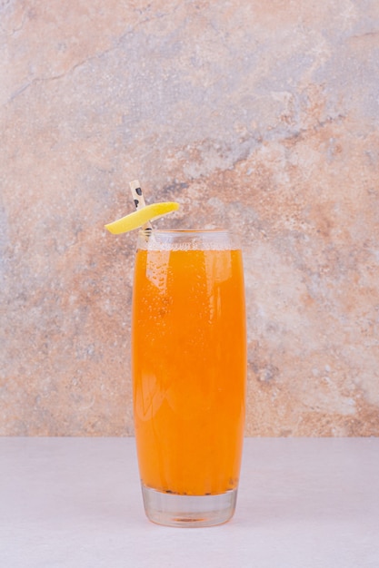 Orangensaft mit Fruchtscheiben und Gewürzen auf weißem Tisch.