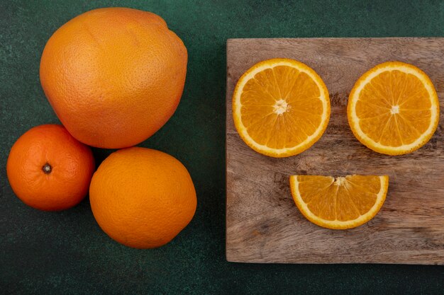 Orangenscheiben der Draufsicht auf Schneidebrett mit Grapefruit auf grünem Hintergrund