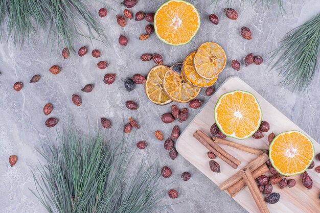 Orangenscheiben mit Hüften und Zimt auf einer Holzplatte