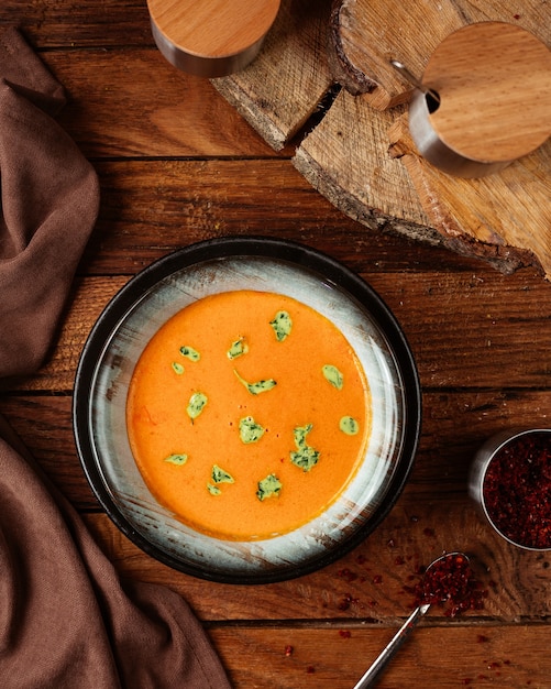 Orangensuppe der Draufsicht mit Blättern auf dem hölzernen Schreibtischnahrungsmittelmahlzeit