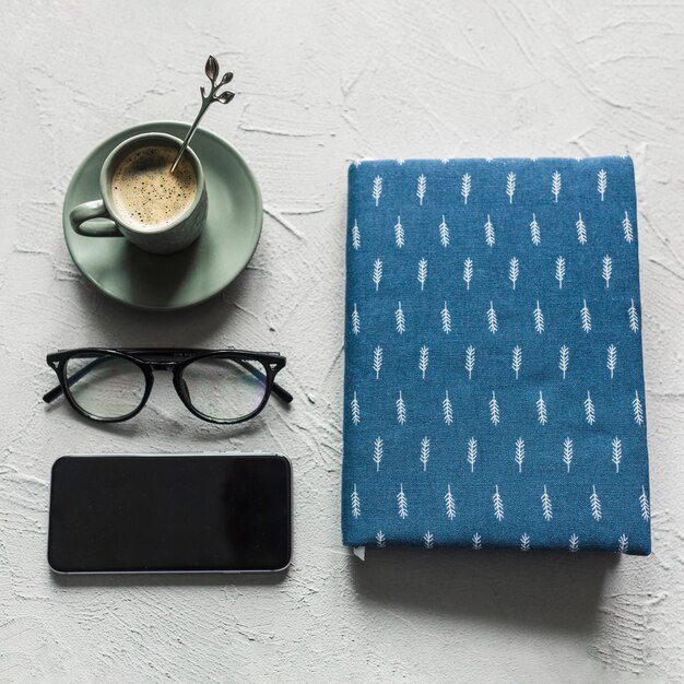 Ordentlich angeordnetes Notizbuch mit Gläsern und Kaffee