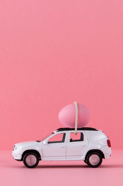 Kostenloses Foto osterauto mit rosafarbenem ei und hintergrund