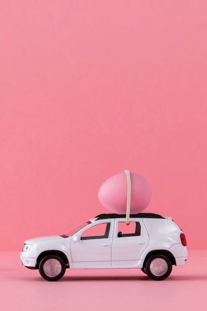 Osterauto mit rosafarbenem Ei und Hintergrund