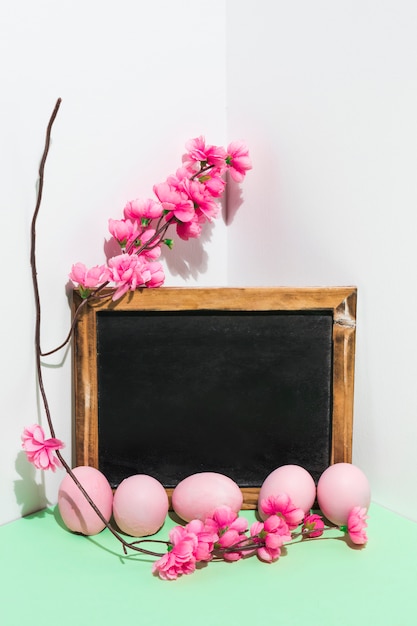 Kostenloses Foto ostereier mit tafel und blumen verzweigen sich auf tabelle