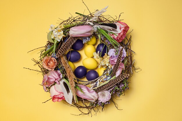 Osterkarte. Gemalte Ostereier im Nest auf gelb