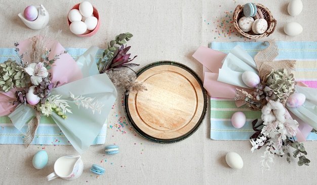 Osterkomposition mit Blumen, Eiern und Holzraum für Text in Pastellfarben flach legen.
