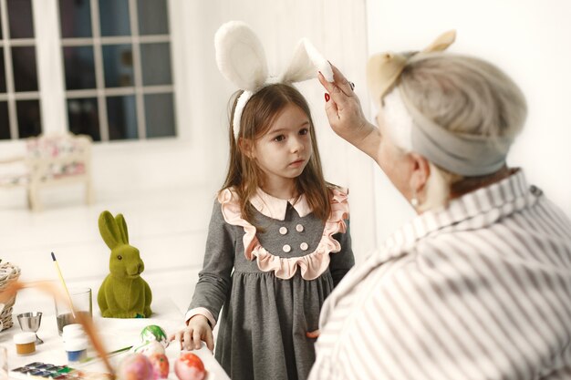 Osterkonzept. Kleines Mädchen und ihre Großmutter färben Eier für Ostern.