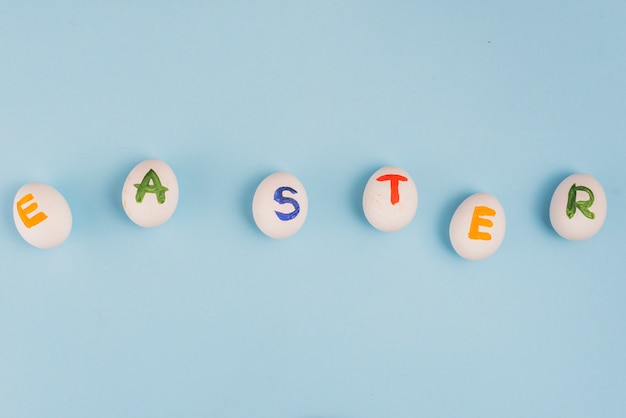 Ostern-Aufschrift auf weißen Eiern auf blauer Tabelle