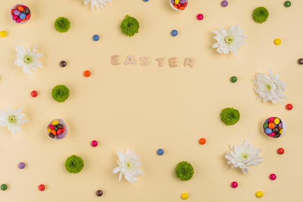 Ostern-Aufschrift mit Blumen und Süßigkeiten auf Tabelle