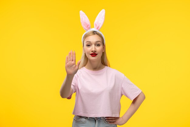 Ostern entzückendes hübsches junges blondes Mädchen mit Hasenohren, das Stoppschild mit der Handgeste zeigt