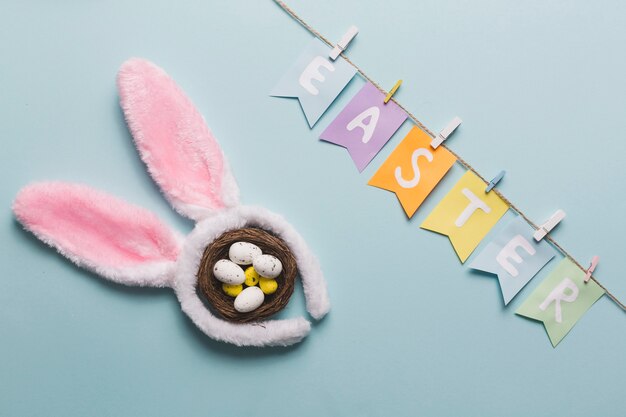 Osternschrift in der Nähe von Kaninchenohren und Nest