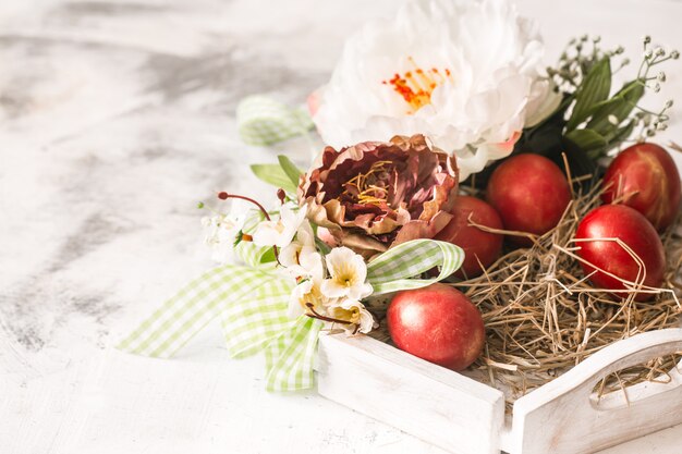 Ostertisch mit einem Korb und roten Eiern mit Blumen