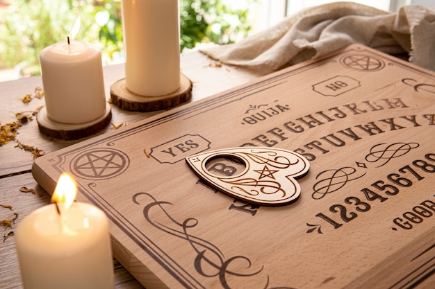 Kostenloses Foto ouija-brett mit hohem winkel und kerzenanordnung