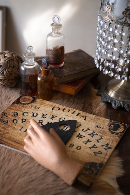 Ouija-Brett und gefälschte Hand auf dem hohen Winkel des Tisches