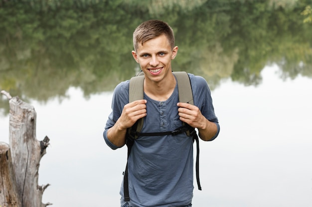 Kostenloses Foto oung junge, der an der kamera nahe einem see lächelt