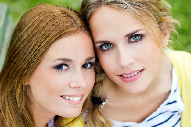 Outdoor Portrait von zwei schöne junge Frauen posiert im Park