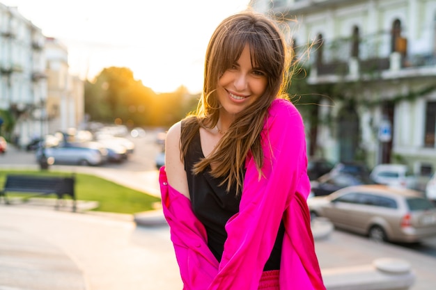 Outdoor-Sommerporträt einer gutaussehenden Frau in stilvoller rosa Jacke.