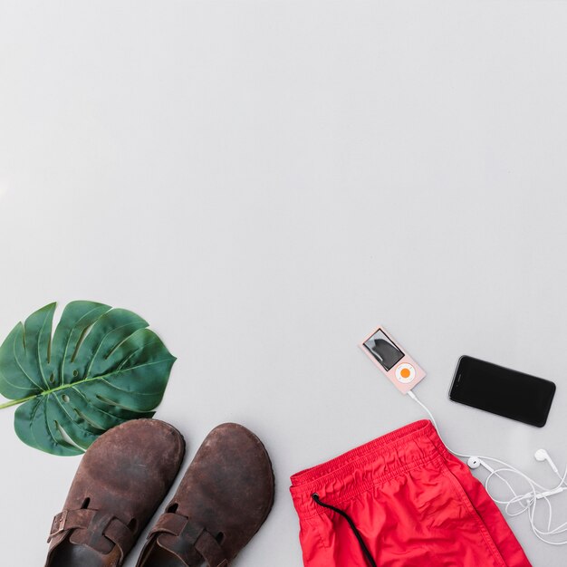 Outfits, Paar Schuhe, Blatt, Handy und MP3-Player auf grauem Hintergrund