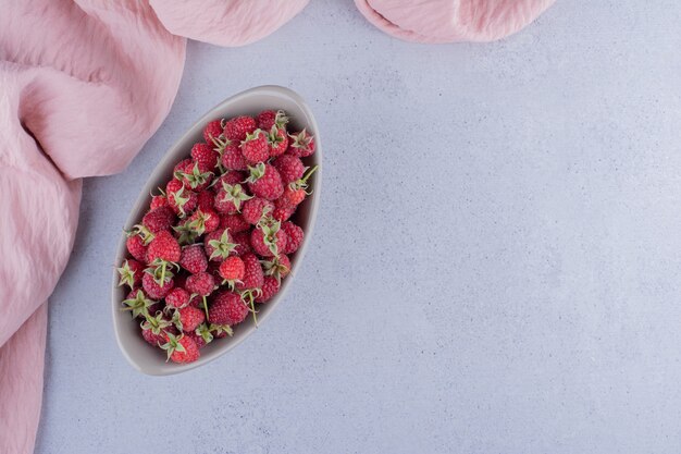 Ovale Schüssel mit Himbeeren auf Marmorhintergrund bestückt.