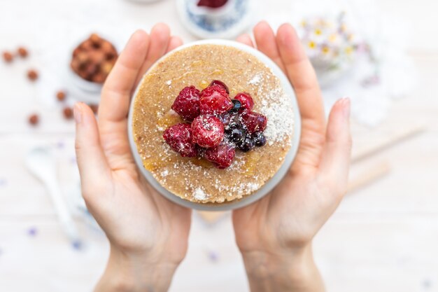 Overhead-Nahaufnahmeaufnahme von rohen veganen Pfannkuchen mit Honig und Beeren