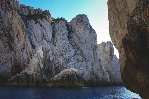 Ozean, umgeben von den felsigen Klippen, die unter dem blauen Himmel schimmern - ideal für Tapeten