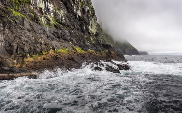 Ozean vor einem felsigen Berg unter den düsteren Wolken