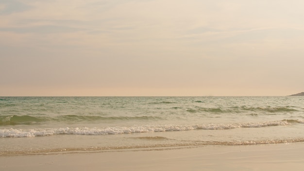 Ozeanstrand bewegt auf tropischen Strand zur Sonnenuntergangzeit wellenartig