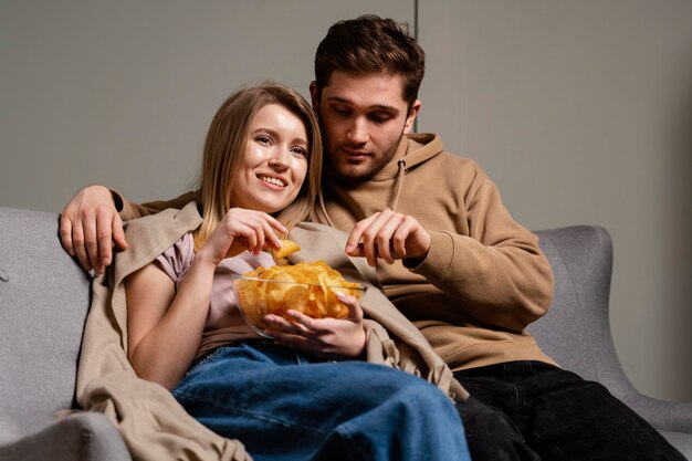 Paar auf der Couch fernsehen und Pommes essen
