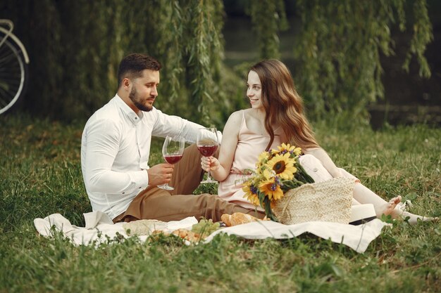 Paar auf einem Feld. Brünette in einem weißen Kleid. Paar sitzt auf einem Gras.