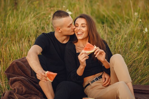Paar auf einem Feld. Frau in einer schwarzen Bluse. Menschen mit Wassermelone.