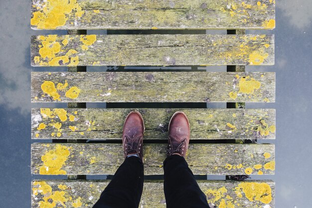 Paar braune Lederschuhe, die auf einer alten grauen und gelben Brücke stehen