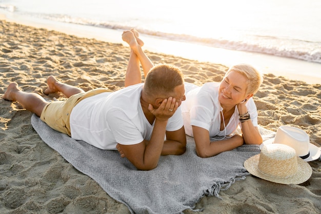 Paar, das auf Handtuch am Strand legt