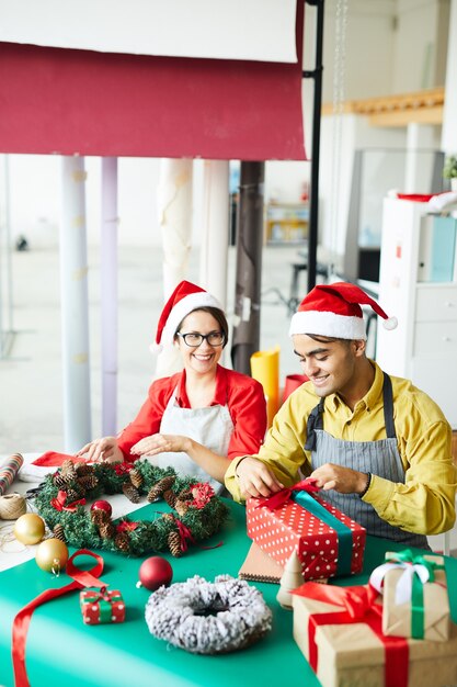 Paar, das Weihnachtsdekoration vorbereitet und Geschenke einwickelt