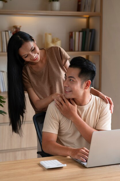 Paar, das zu Hause am Laptop arbeitet, während es liebevoll ist