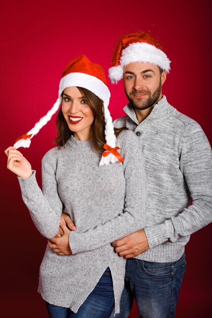 Paar gekleidet mit Winterkleidung und Santa Hut auf rotem Hintergrund mit sno