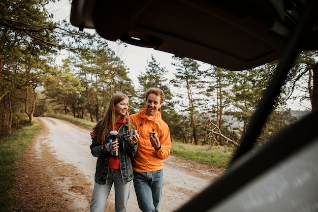 Kostenloses Foto paar genießt heißes getränk während eines roadtrips mit dem auto