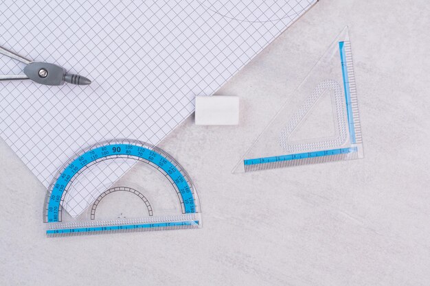 Paar Geometriekompasse und Papier auf weißem Tisch.