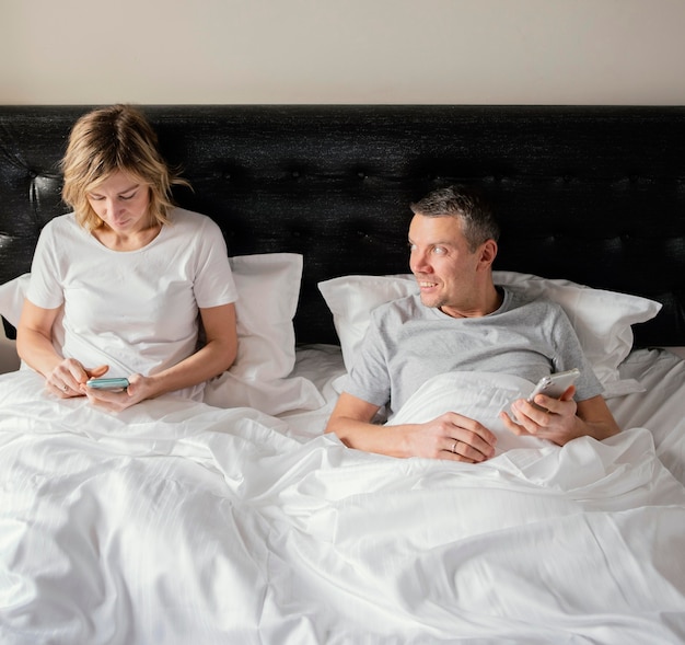 Paar im Bett mit Handys