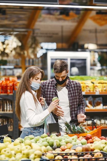 Kostenloses Foto paar in der medizinischen schutzmaske in einem supermarkt.